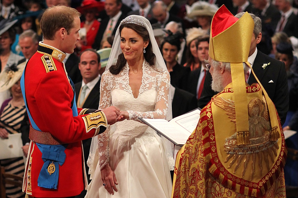 Nunta Prințului William și a lui Kate Middleton din anul 2011. Sunt în înteriorul Westminster Abbey și un preot îi căsătorește. Preotul poartă auriu cu roșu, Kate are rochia de mireasă, Prințul William poartă uniforma roșie, cu o curea albastră