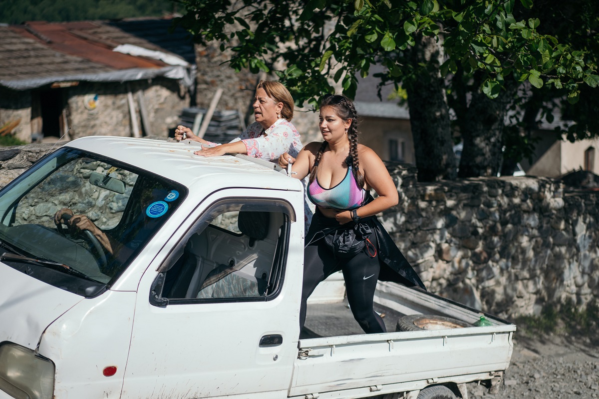 Maria Spernața purtând colanți negri și un tricou gri alături de mama sa, Adriana Trandafir în timp ce se află în remorca unui camion alb la competiția Asia Express: Drumul Împăraților