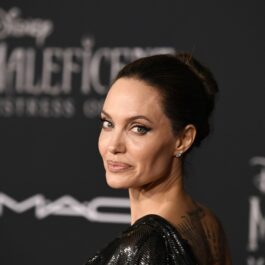 Angelina Jolie într-o rochie neagră în timp ce pozează pe covorul roșu la premiera filmului Maleficent