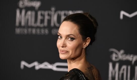Angelina Jolie într-o rochie neagră în timp ce pozează pe covorul roșu la premiera filmului Maleficent