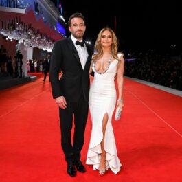Ben Affleck la costum negru pe covorul roșu, alături de Jennifer Lopez care poartă o rochie albă mulată în timp ce participă la Festivalul de Film de la Veneția 2021 la premiera filmului The Last Duel