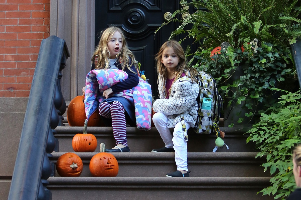 Tabitha Hodge și Marion Loretta Elwell, gemenele actriței Sarah Jessica Parker în timp ce stau pe o scară decorată cu dovleci de Halloween