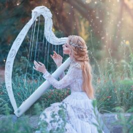 O femeie frumoasă care poartă o rochie albă și se folosește de talentul său ascuns pentru a cânta la harpă