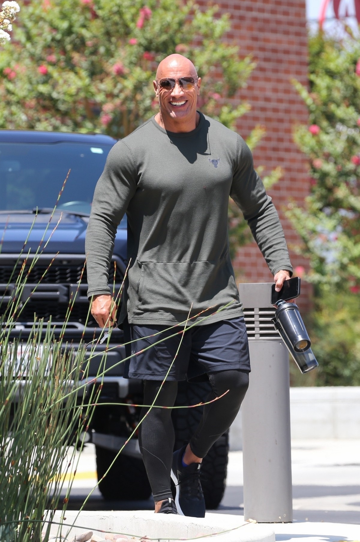 Dwayne Johnson într-un tricou verde și o pereche de pantaloni negri de sport în timp ce părăsește sala de sport din Los Angeles