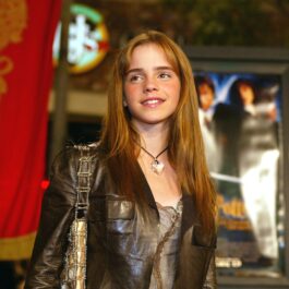 Emma Watson cu părul lung purtând o jachetă maro la premiera filmelor Harry Potter