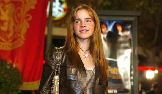 Emma Watson cu părul lung purtând o jachetă maro la premiera filmelor Harry Potter