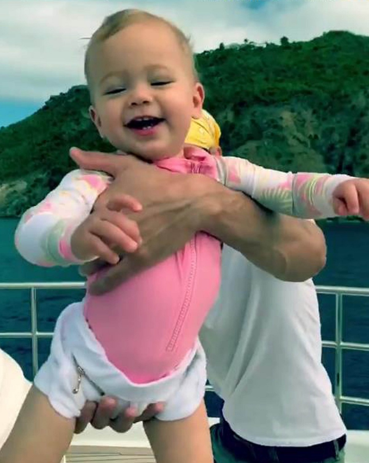 Fetița lui Enrique Iglesias, Marry Iglesias în timp ce poartă un tricou roz și este riidicată în aer de tatăl său