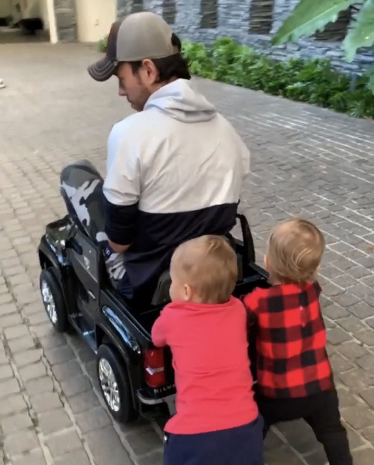 Gemenii lui Enrique Iglesias, Nicholas Iglesias și Lucy Iglesias, în timp ce îl plimbă pe cântăreț într-o mașină de jucărie neagră