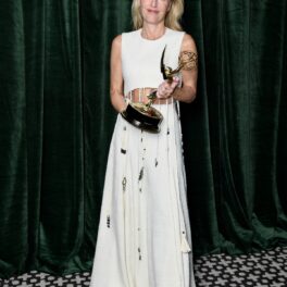 Gillian Anderson într-o rochie albă cu paiete în timp ce ține în mână trofeul de la Premiile Emmy 2021