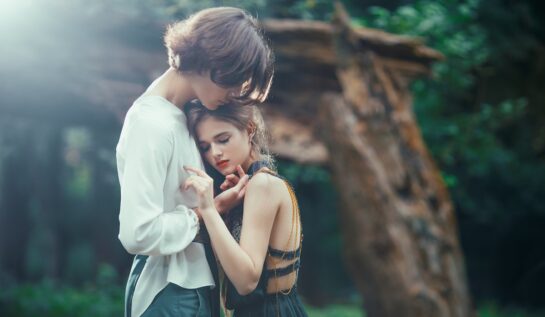 Un cuplu de îndrăgostiți în timp ce se țin în brațe într-o pădure