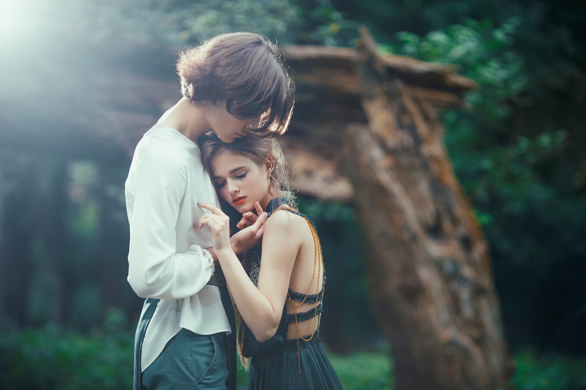 Un cuplu de îndrăgostiți în timp ce se țin în brațe într-o pădure
