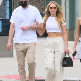 Jennifer Lawrence într-un top alb și o pereche de pantaloni crem în timp ce se află la brațul soțului său, Cooke Maroney