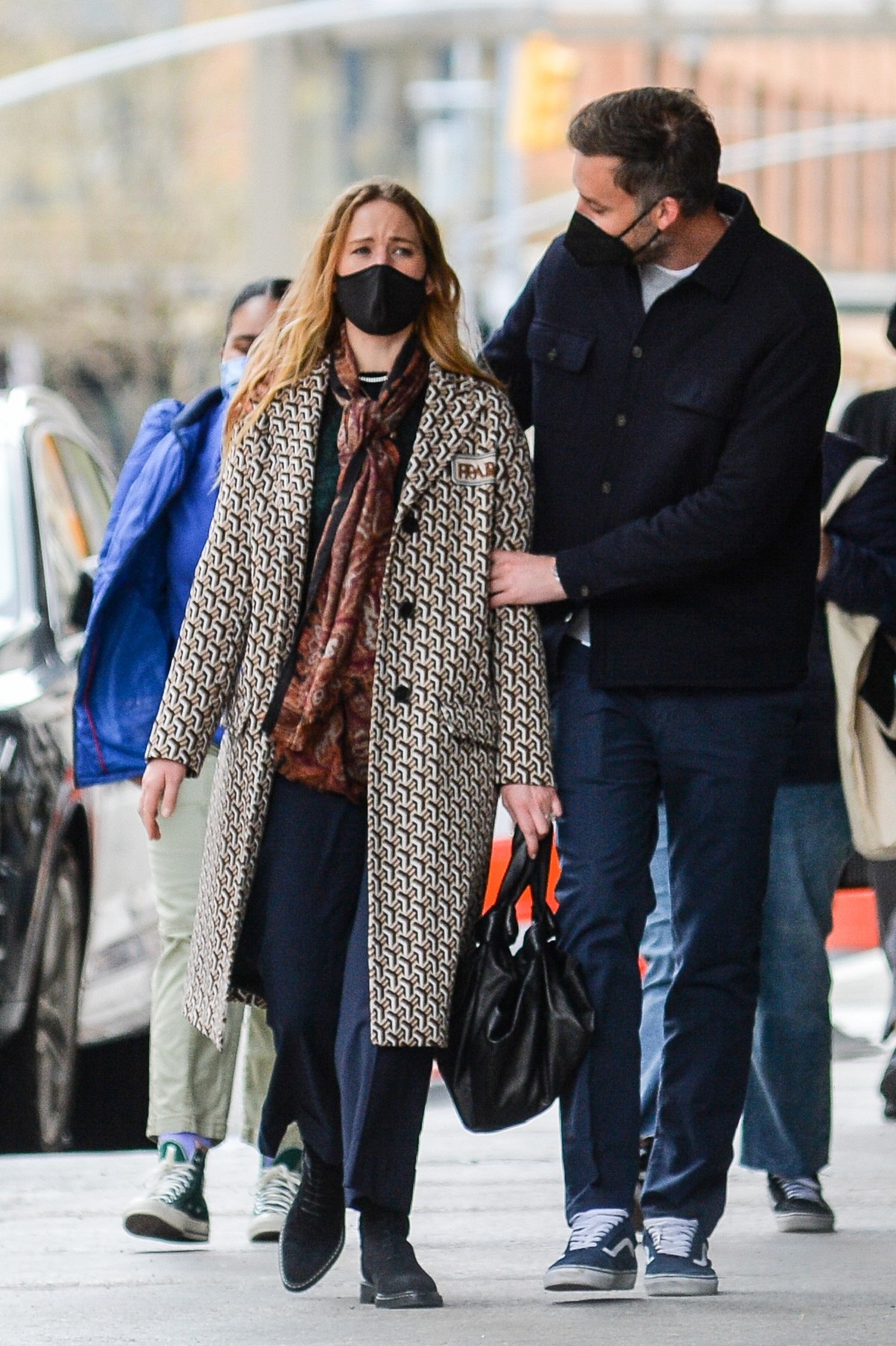 Jennifer Lawrence într-un palton lung în carouri cu mască pe față în timp ce merge alături de soțul său Cooke Maroney pe străzile din New York