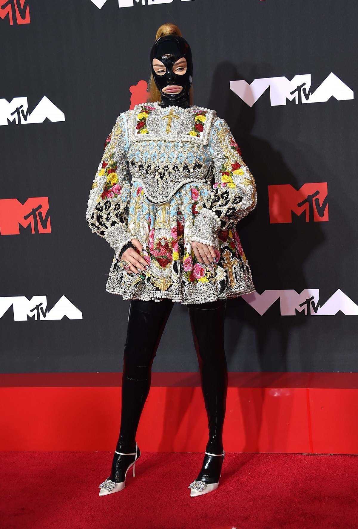 Kim Petras purtând o rochie scurtă cu inspirații religioase și o mască din latex negru pe covorul roșu la MTV VMA 2021
