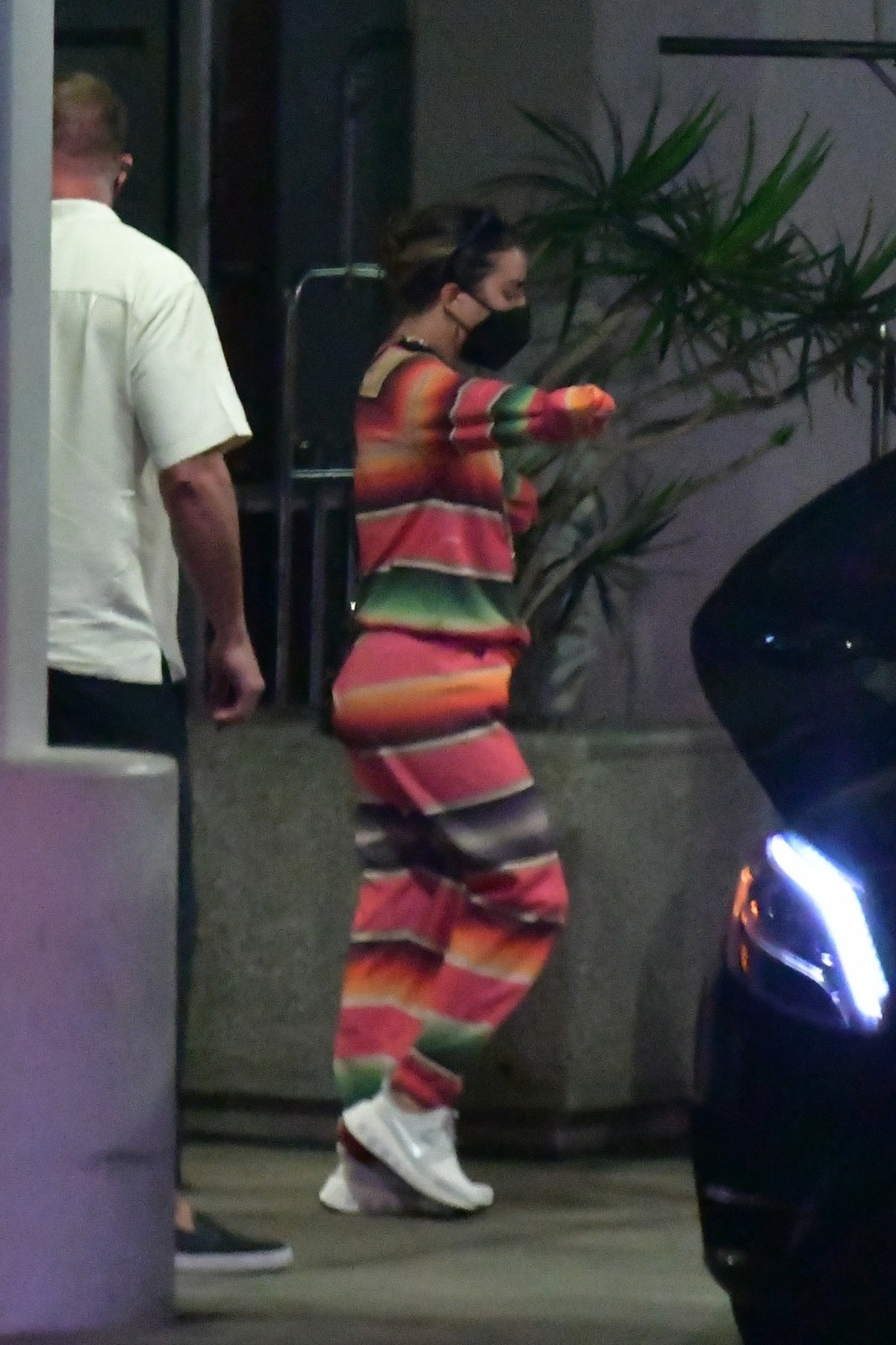 Lady Gaga într-un costum de trening cu dungi roz, verzi și portocalii, în timp ce pleacă din aeroportul din Los Angeles