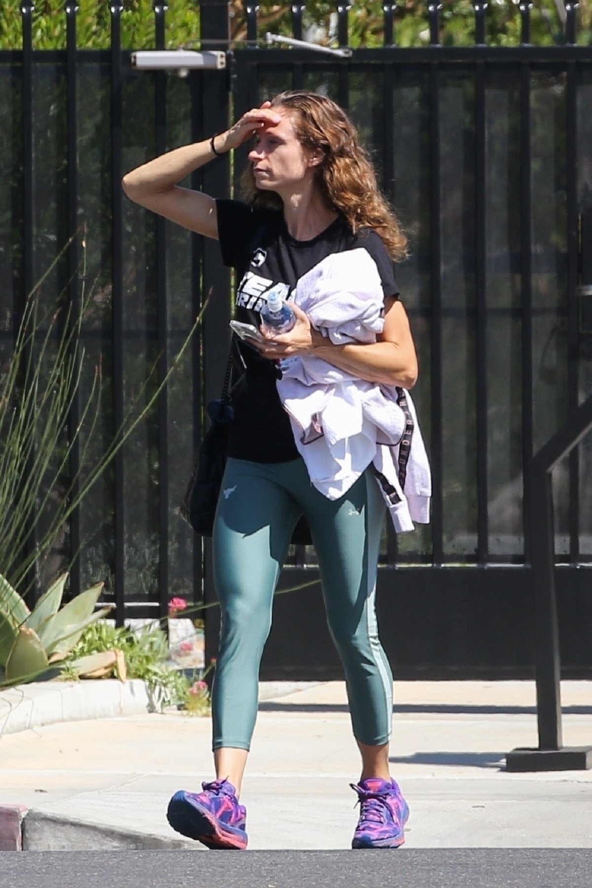 Lauren Hashian așezându-și părul și purtând o pereche de colanți verzi și un tricou negru în timp ce părăsește sala de sport din Los Angeles