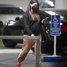Olivia Munn într-un hanorac negru și o pereche de pantaloni crem în timp ce merge spre mașina sa dintr-o parcare subterană