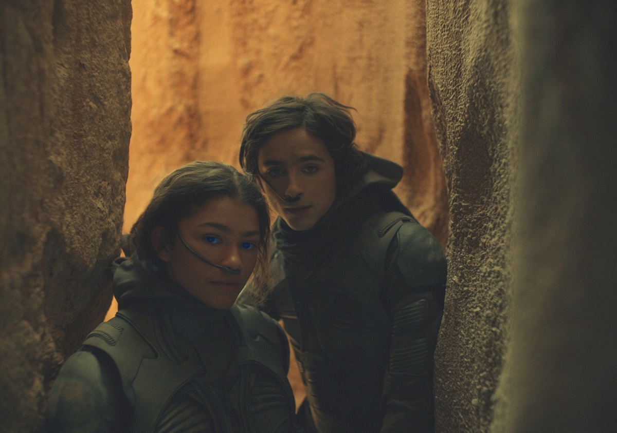 Zendaya într-un costum militar gri și actorul Timothee Chalament în costum în timp ce se află într-un tunel într-una din scenele din filmul Dune care a fost lansat la Festivalul de Film de la Veneția din 2021