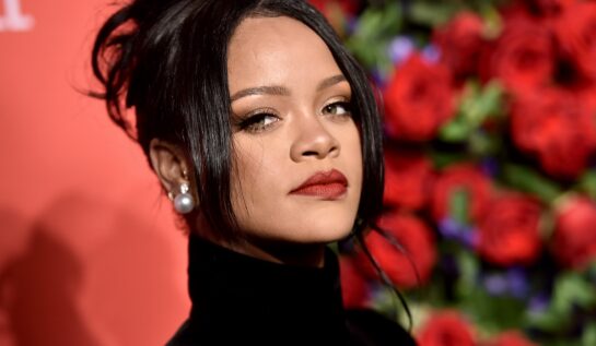 Rihanna cu părul prins în timp ce pozează în fața unui panou roșu