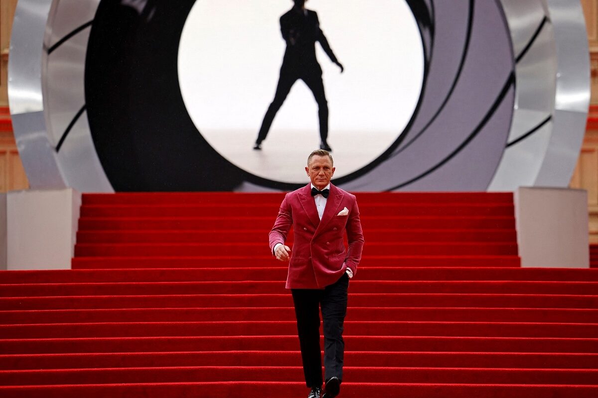 Daniel Craig într-un costum cu sacou roz în timp ce coboară scările acoperite de covorul roșu la premiera filmului James Bond No Time to Die