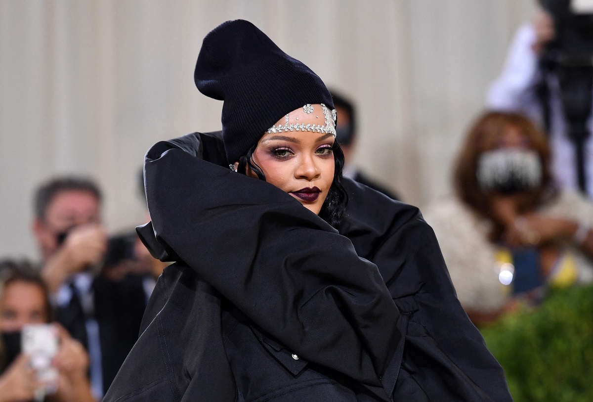 Artista Rihanna într-o rochie neagră cu un fes pe cap în timp ce pozează la Met Gala 2021