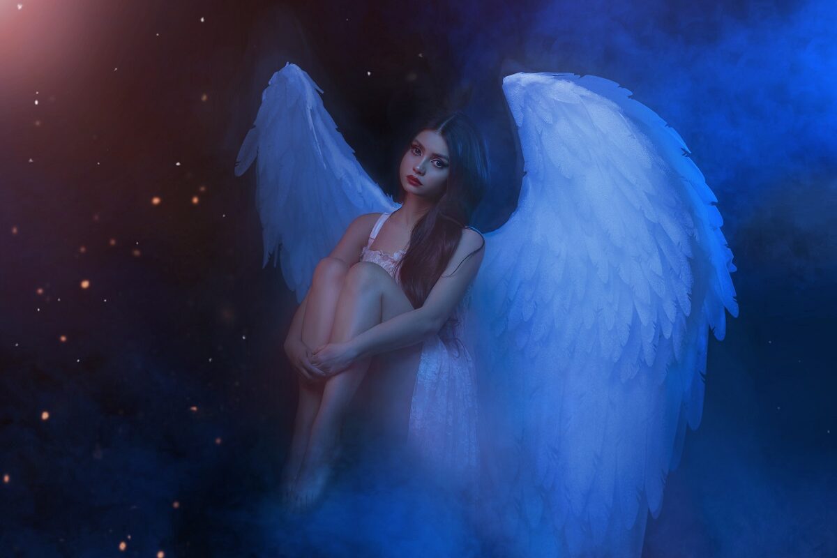 O femeie frumoasă care poartă o rochie albă și aripi de înger în timp ce își ține genunchii între brațe și privește tristă fiind una din acele zodii ghinioniste în ziua de 29 septembrie 2021