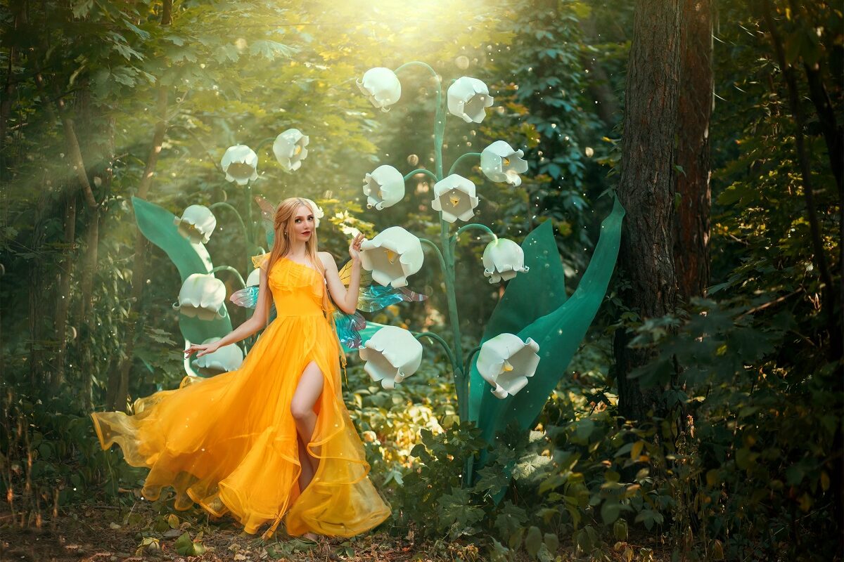 O femeie frumoasă care poartă o rochie galbenă și se află într-o pădure printre flori albe în timp ce portretizează una din acele zodii noroacoase în ziua de 1 octombrie 2021