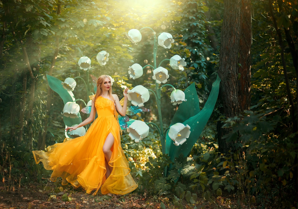 O femeie frumoasă care poartă o rochie galbenă și se află într-o pădure printre flori albe în timp ce portretizează una din acele zodii noroacoase în ziua de 1 octombrie 2021