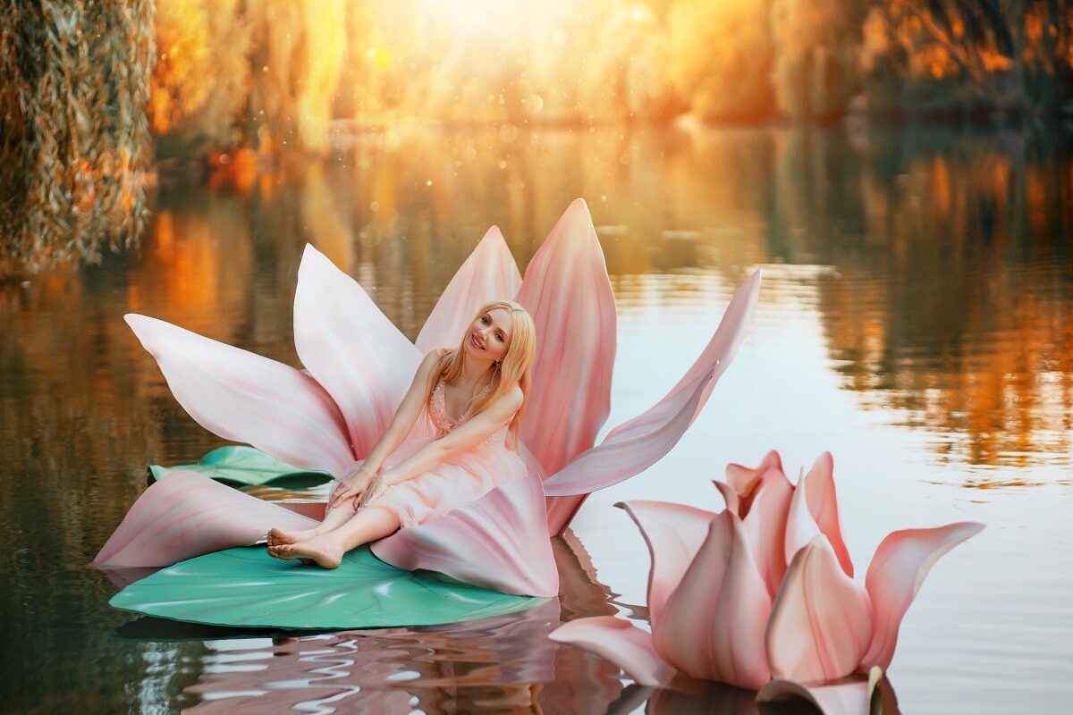 O femeie frumoasă care poartă o rochie roz și stă pe o floare de nufăr în mijlocul unui lac în timp ce reprezintă una din acele zodii norocoase în ziua de 29 septembrie 2021