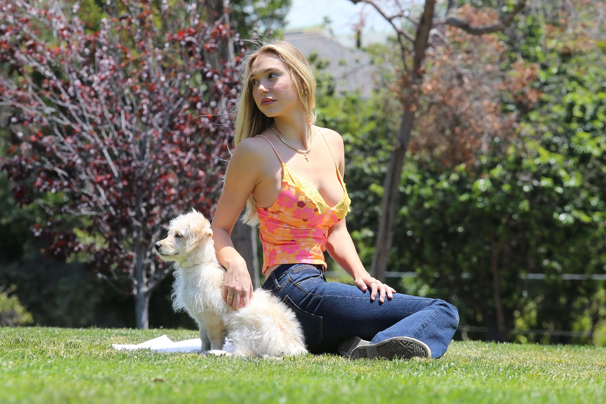 Alexis Ren a mers în parc alături de câinele ei, Angel. Ea poartă blugi și o bluză portocalie, decoltată. Stă pe iarbă și se joacă alături de Angel, un câine alb