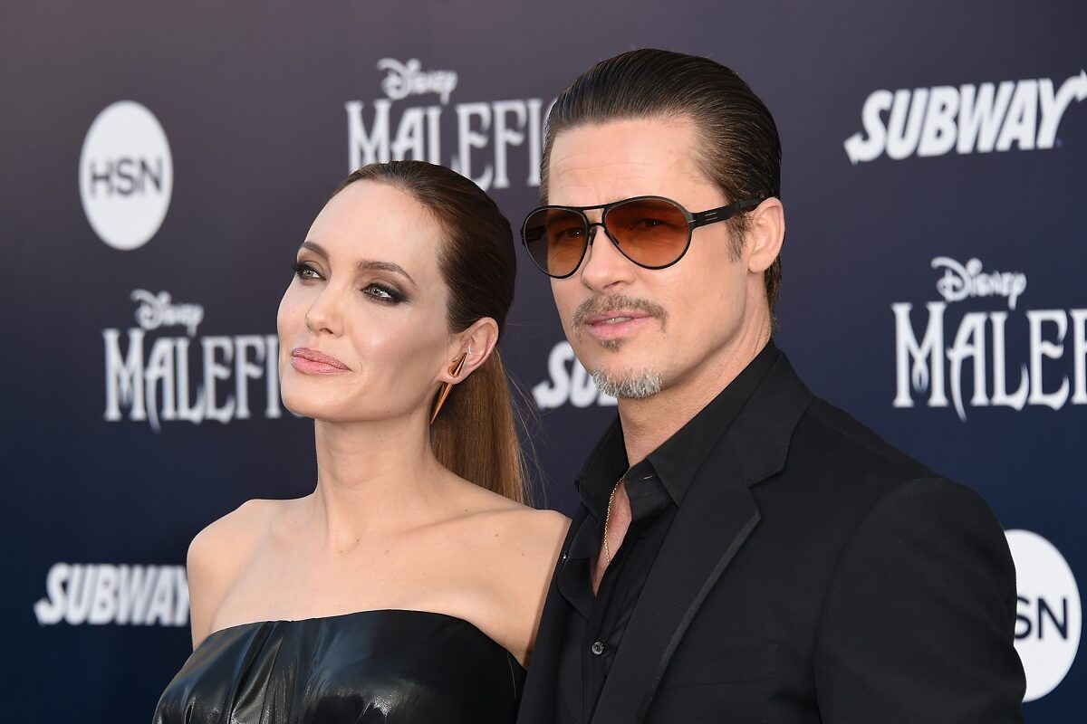 Angelina Jolie și Brad Pitt la premiera Maleficent. Amândoi poartă negru. Brad Pitt e îmbrăcat într-un costum, Angelina într-o rochie neagră fără bretele