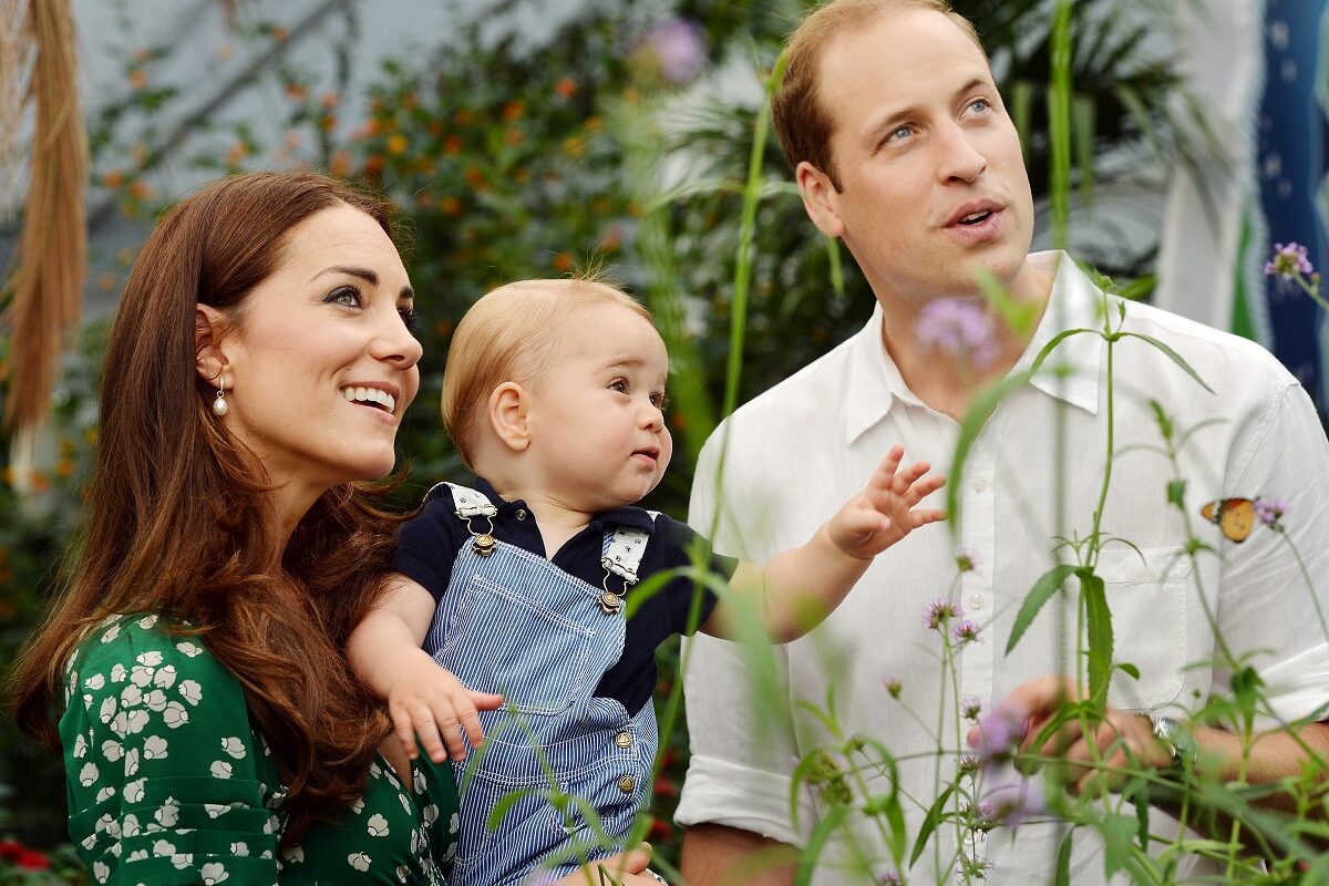 Prințul William, Kate Middleton și Prințul George. Ea poartă o rochie verde, el poartă bej, George poartă o salopetă albastră