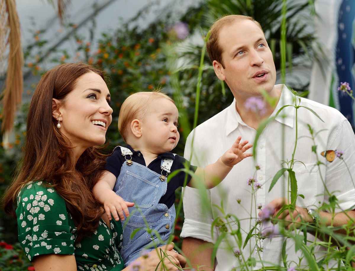 Prințul William, Kate Middleton și Prințul George. Ea poartă o rochie verde, el poartă bej, George poartă o salopetă albastră