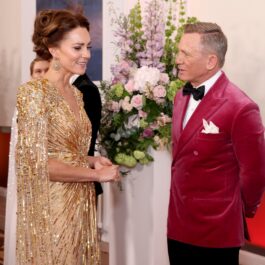 Kate Middleton și Daniel Craig, la premiera filmului No Time To Die, din 2021. Ea poartă o rochie aurie, cu mâneci până la pământ. Craig poartă o jachetă din catifea roz și pantaloni negri. Kate s-a numărat printre membrii Familiei Regale la premierele Bond de-a lungul anilor