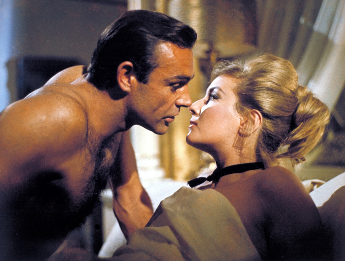 Sean Connery în filmul From Russia With Love, lansat în anul 1964. Nu are cămașă și se apleacă peste o femeie, s-o sărute