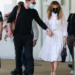 Jennifer Lopez și Ben Affleck, fotografiați în timp ce se țin de mână. Sunt îmbrăcați în haine elegante, demne de un eveniment luxos