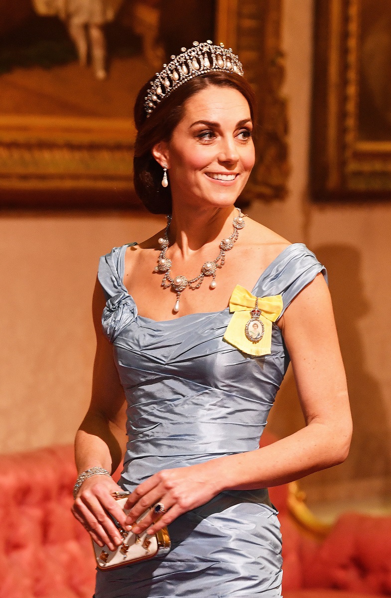 Kate Middleton, în timpul vizitei de stat a familiei regale din Țările de Jos. A purtat tiara Cambridge și o rochie albastră. Fundal cu lemn portocaliu