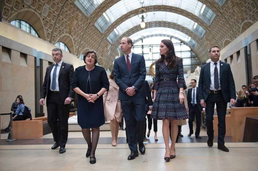 Kate Middleton și prințul William în cadrul unei vizite la Muzeul Orday. El poartă un costum închis la culoare, ea poartă o rochie Chanel de 10.000 de dolari