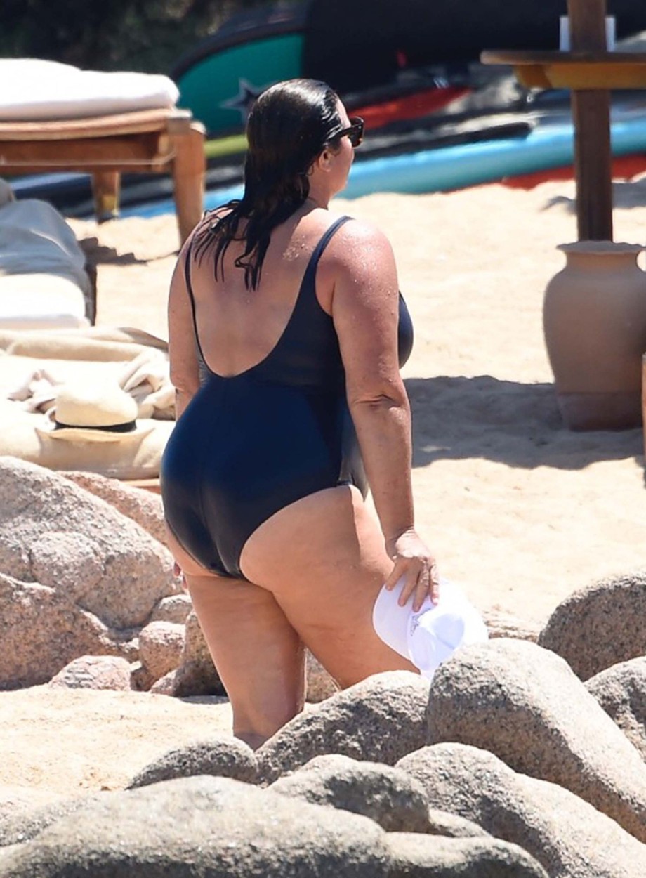Kelly Brosnan, în costum de baie negru, la plajă