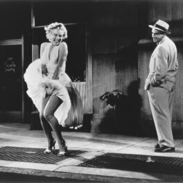 Marilyn Monroe în filmul The Seven Year Itch. Fotografie alb-negru. Poartă celebra rochie albă care se ridică