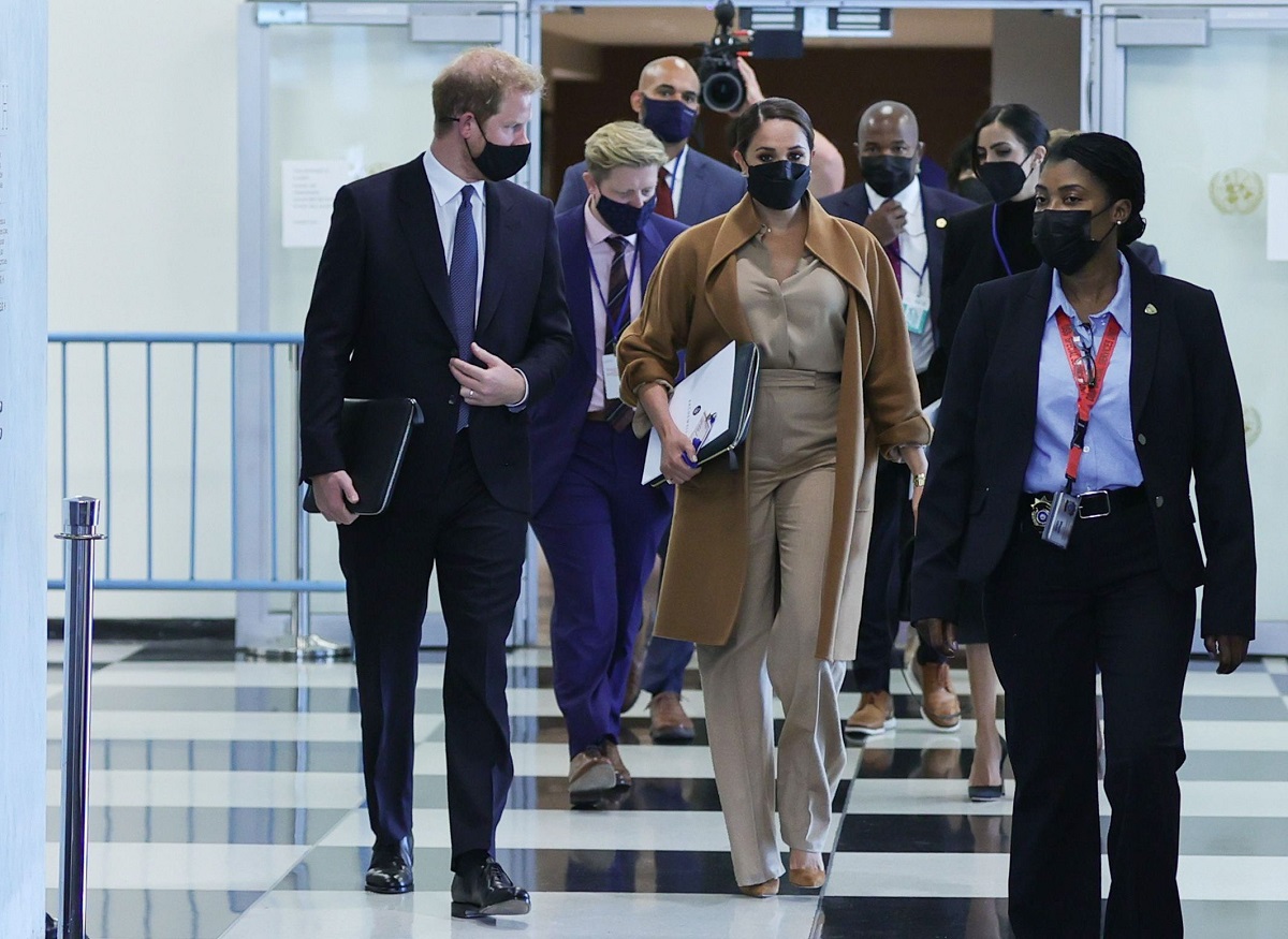 Meghan Markle și Prințul Harry în sediul ONU. Ea poartă bej, el e îmbrăcat în costum închis la culoare. Au un grup în spate, îmbrăcați în costume
