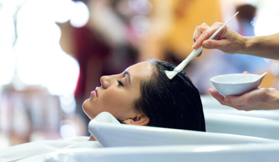 O femeie la un salon de înfrumusețare, care își face un tratament pentru păr