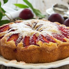 Prăjitura pufoasă cu prune, decorată cu zahăr pe un platou de servire