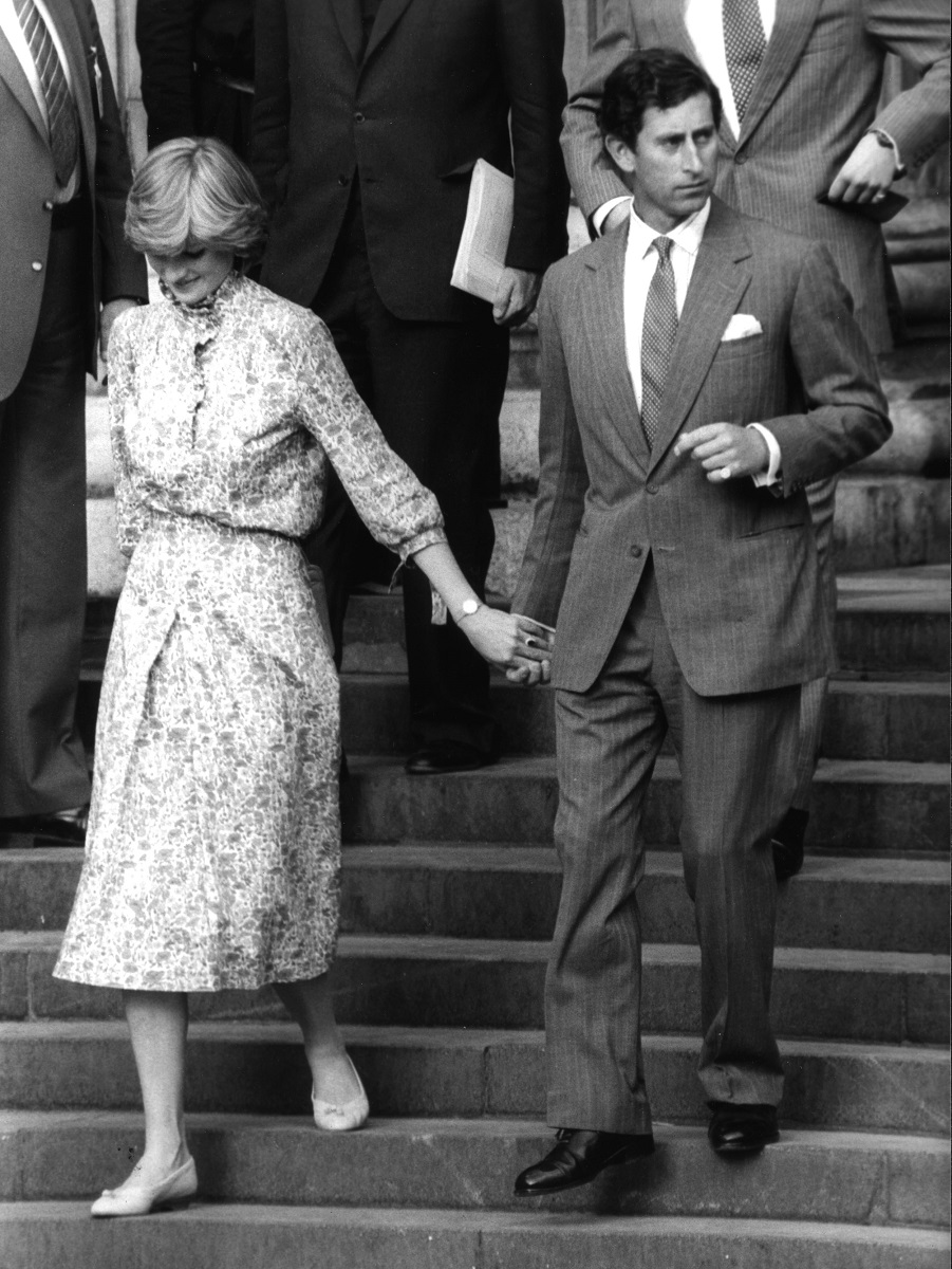 Prințul Charles și Diana pe treptele catedralei, înainte nunții lor. Poză alb=negru. Diana poartă o rochie albastră, Charles are costum negru