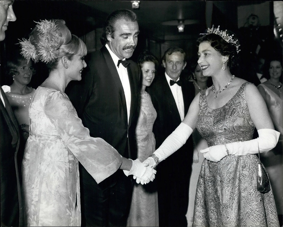 Regina Elisabeta, Sean Cpnnery și soția lui, în 1967, la premiera You Only Live Twice. Elisabeta poartă o rochie lungă și o coroană, Sean poartă un costum