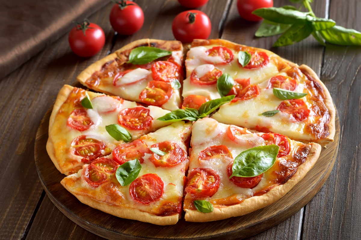 Pizza Margherita porționată în șase pe un platou de lemn