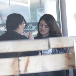 Selena Gomez mănâncă un prânz cu o prietenă. E îmrăcată cu o bluză gri. Prirtena poartă bluză neagră