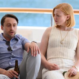 Imagine din sezonul 2 al serialului Succesiunea, cu Culkin și Snook. Stau pe un iaht, mare în spare, fundal alb. E poartă o cămașă albastră, ea poartă o bluză albă. Succesiunea e unul dintre cele mai așteptate seriale care apar în octombrie 2021