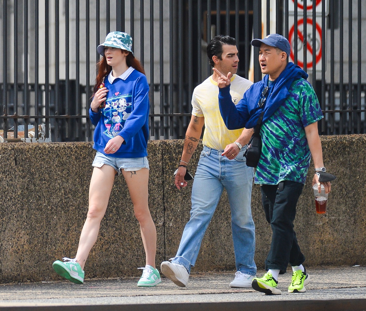 Joe Jonas și Sophie Turner, pe străzile din New York, cu un prieten. Ea poartă pantaloni scurți și o bluză albastră, el poartă blugi și tricou galben