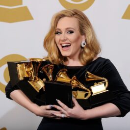Cântăreața Adele în timp ce ține în mână șase premii muzicale în anul 2012